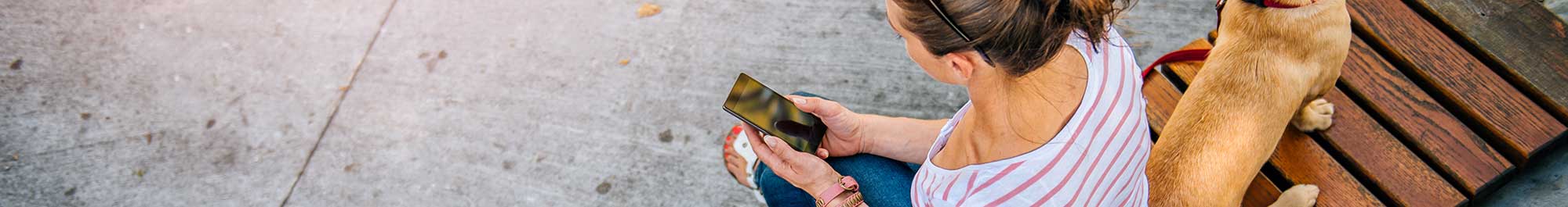 woman using her mobile phone to bank while dog-walking